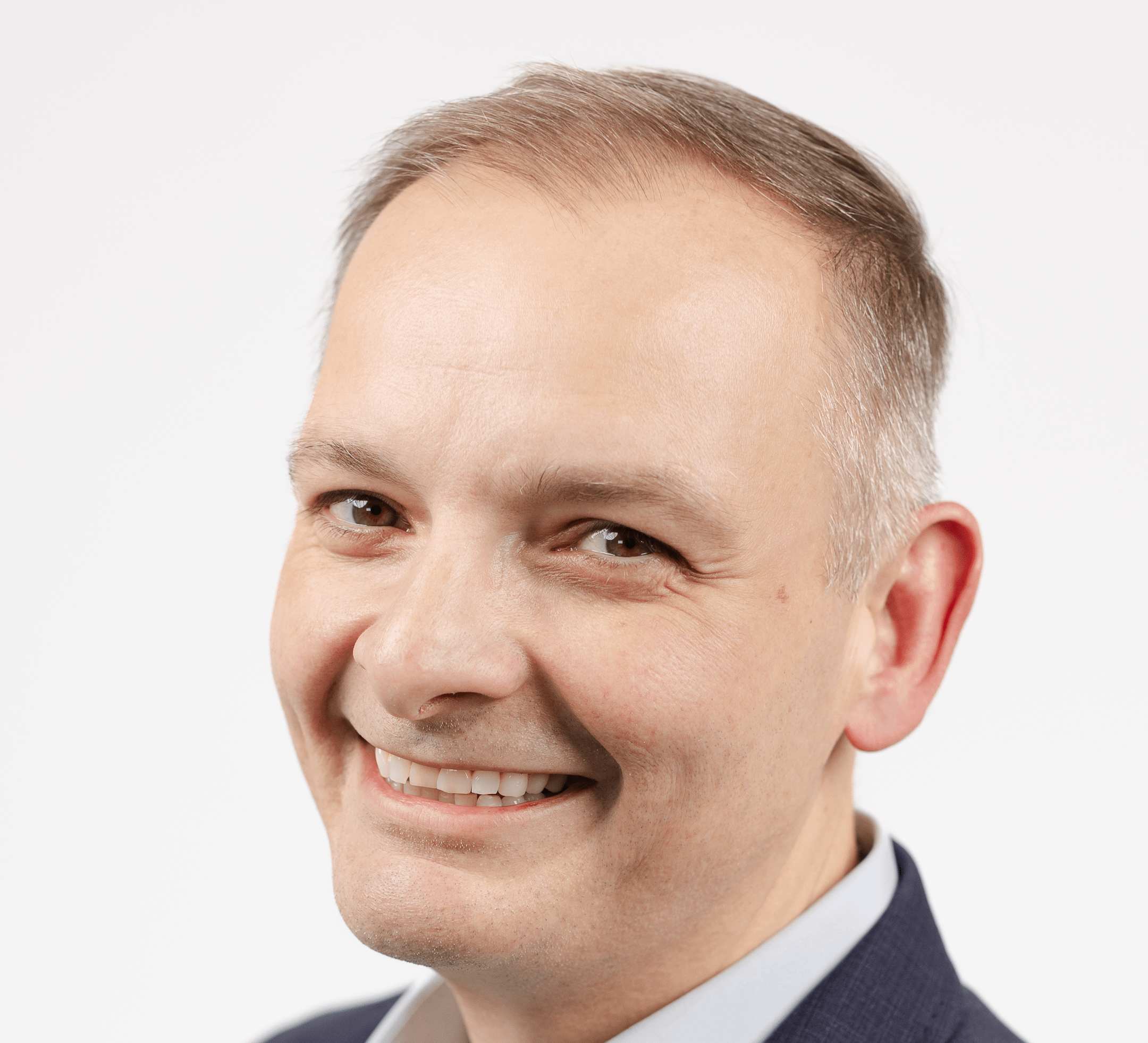 Headshot of Gus Huber, smiling with a white background.